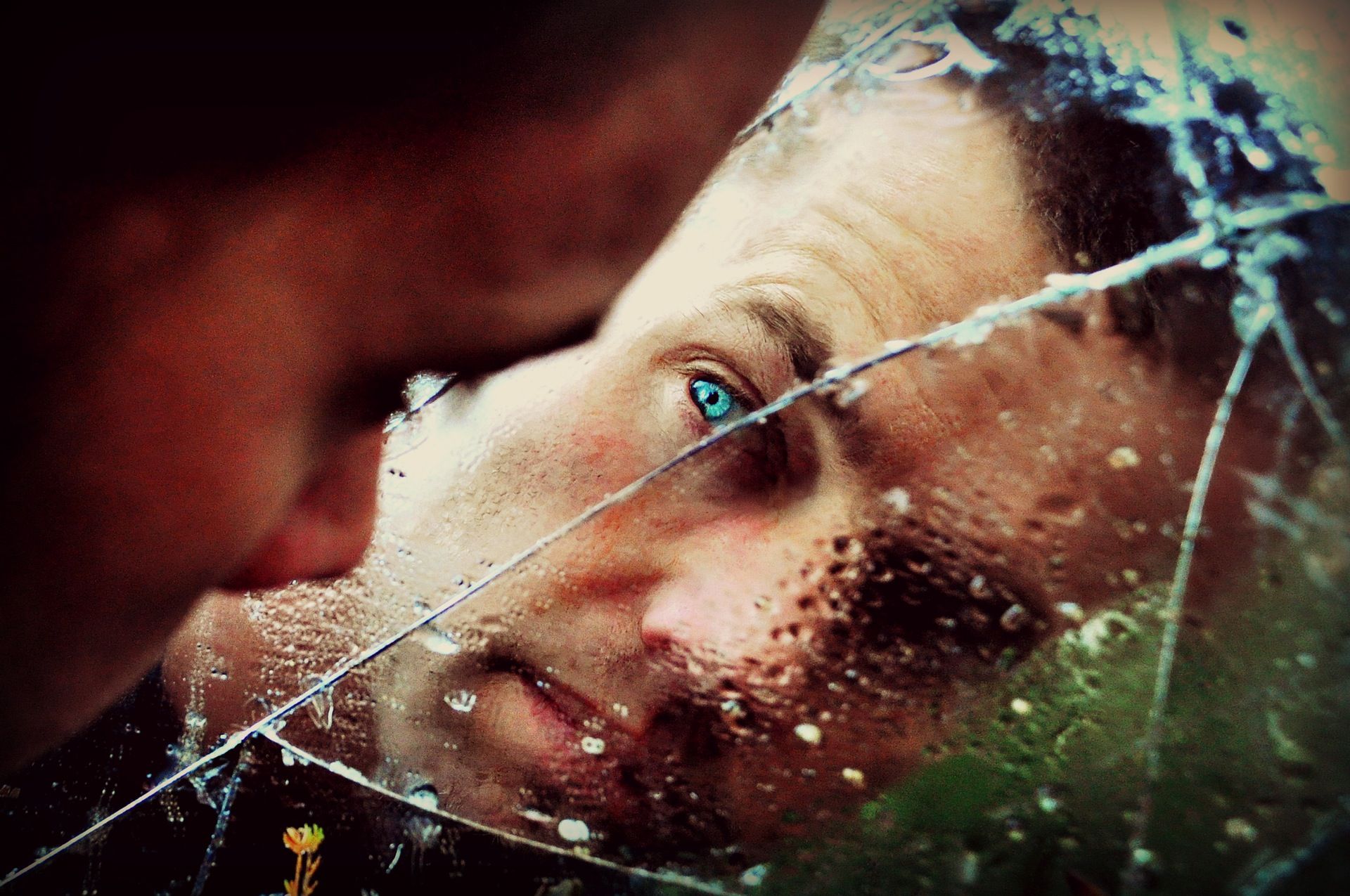 Attractive man looking into broken mirror