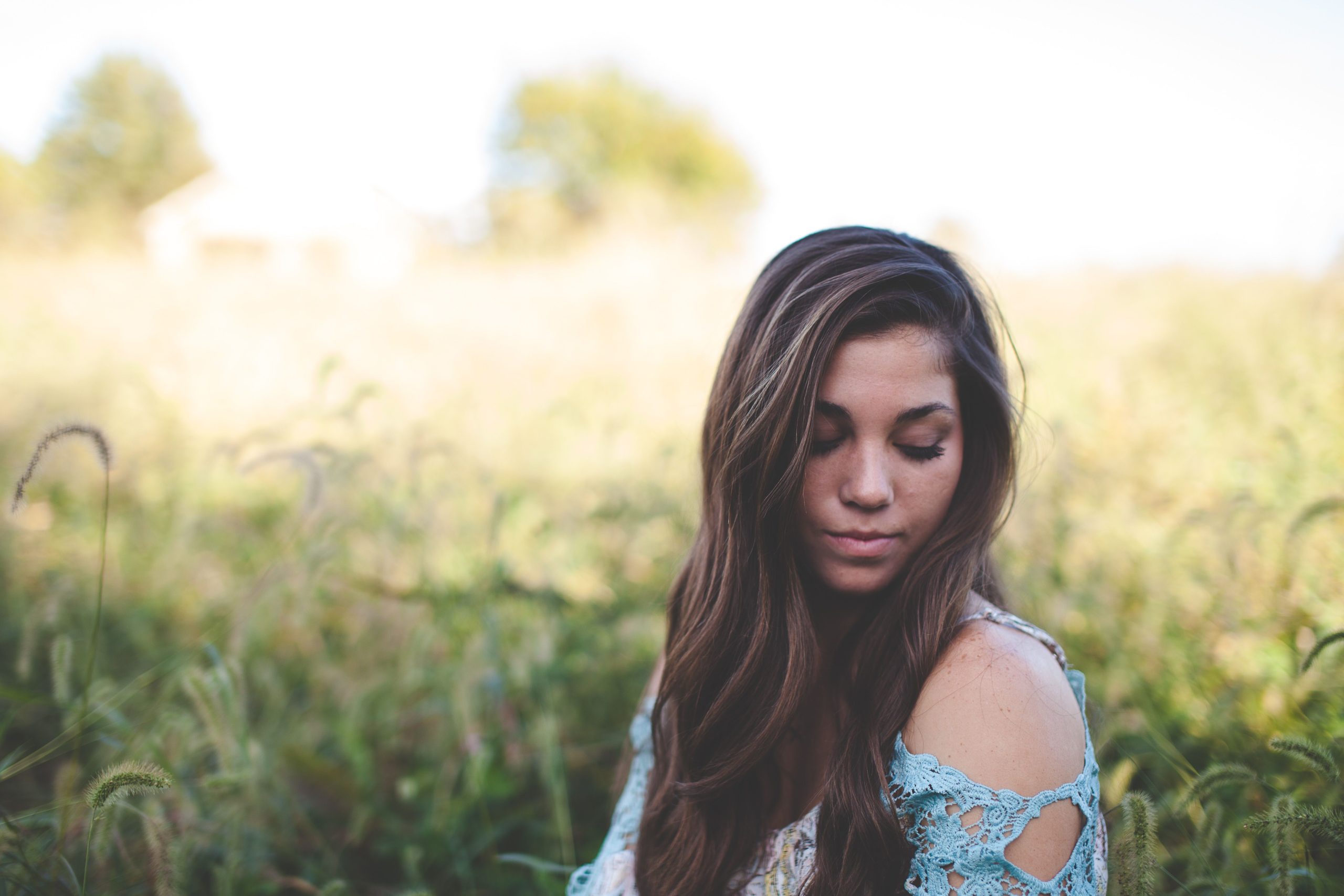 woman in teal off-the-shoulder shirt standing in field