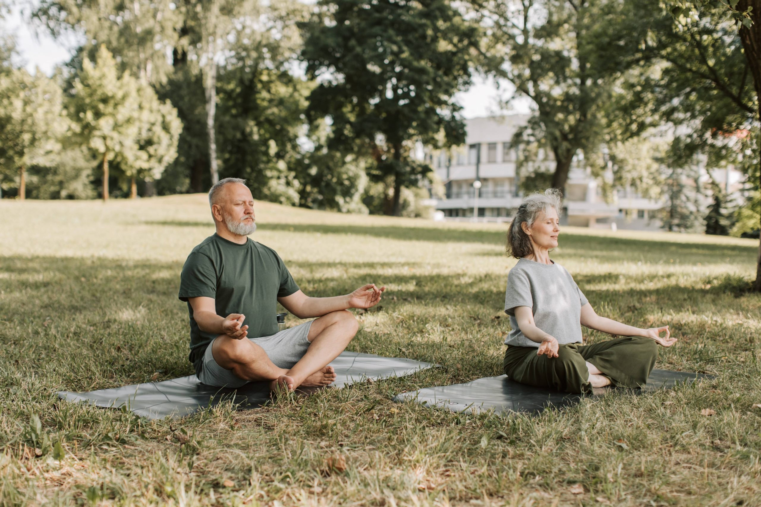 Man and woman sitting in field positioned to meditate.