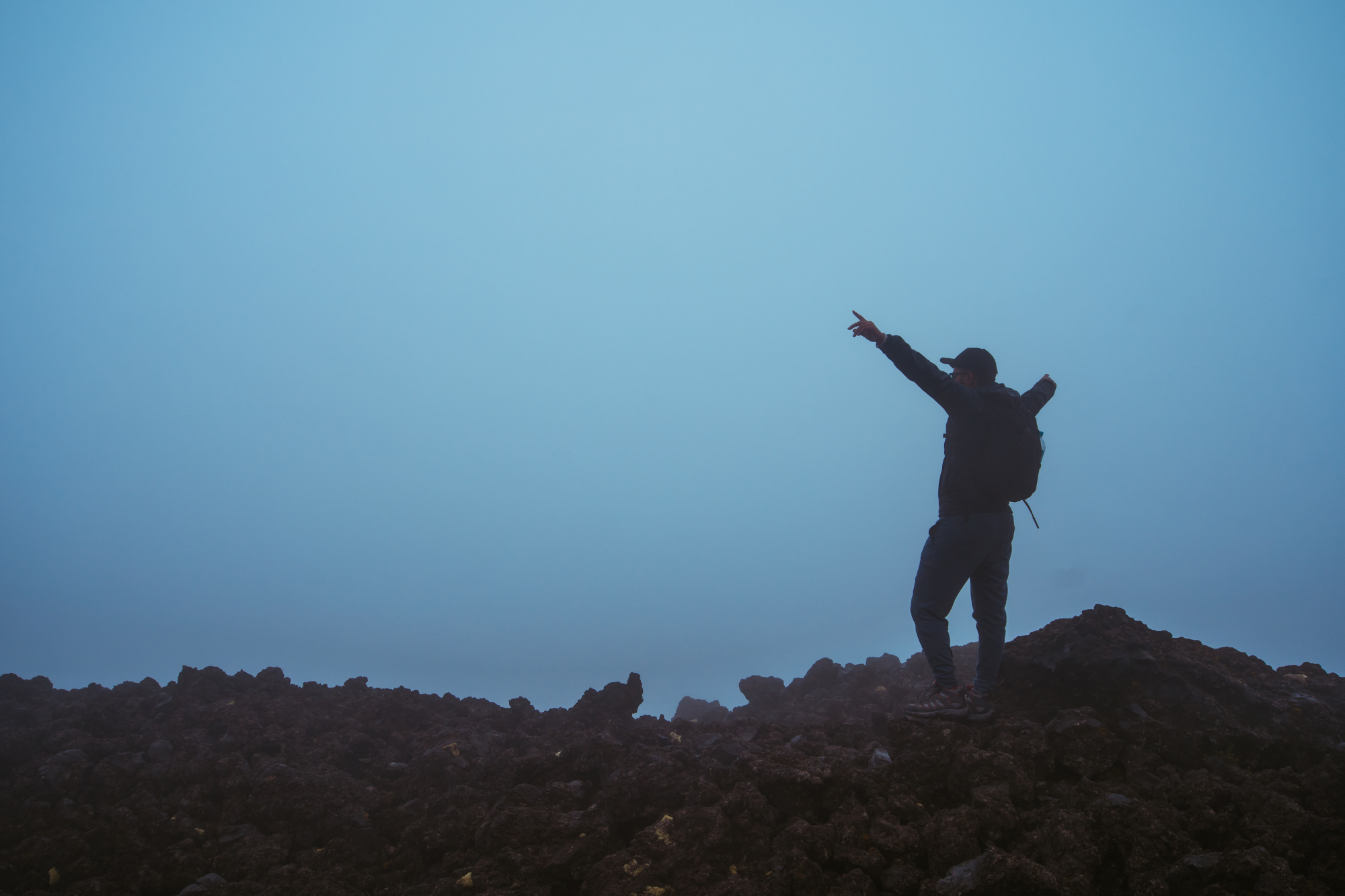 Person at the top of a mountain with hands in the air celebrating. 