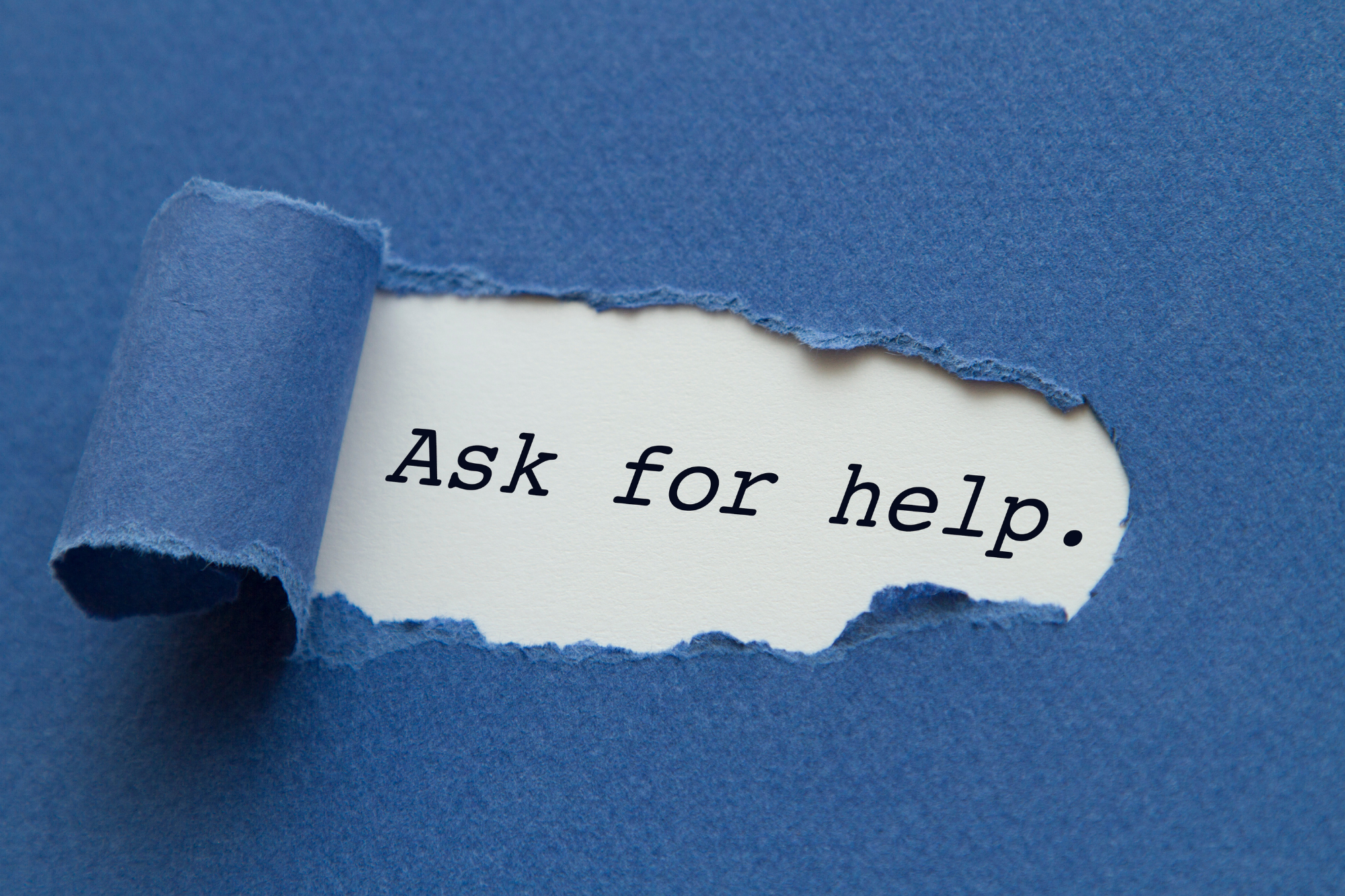 Blue paper torn to reveal the following message "Ask for help."