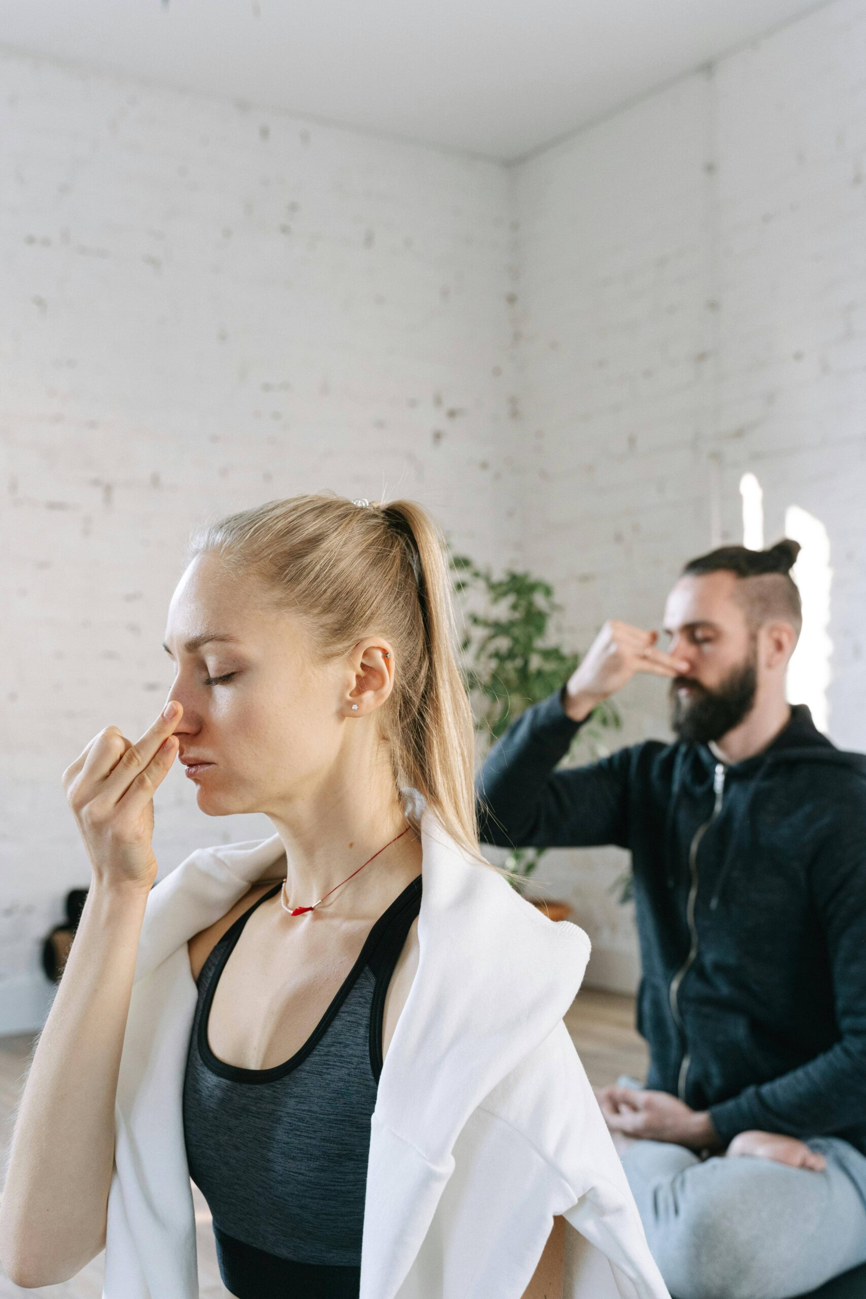 Two adults practicing alternating nostril breathing in meditation class